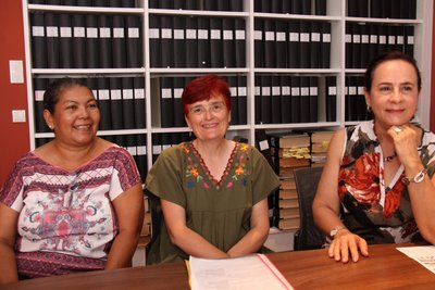 Drei Frauen sitzen nebeneinander an einem Tisch.